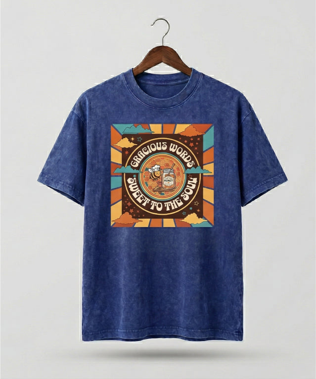 Blue t-shirt with a colorful graphic design on a hanger against a light gray background