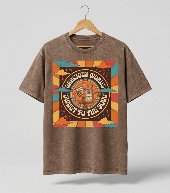 Brown t-shirt with colorful graphic design on a hanger against a gray background