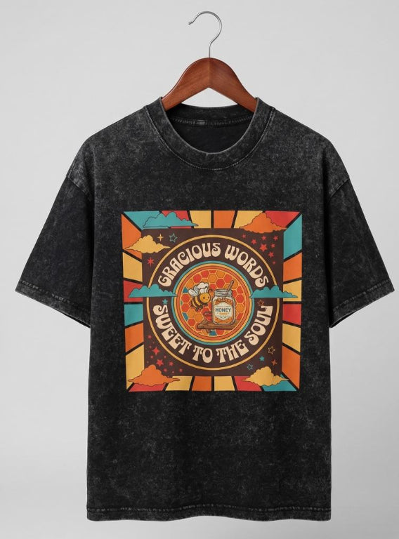 Black t-shirt with colorful graphic design on a hanger against a gray background